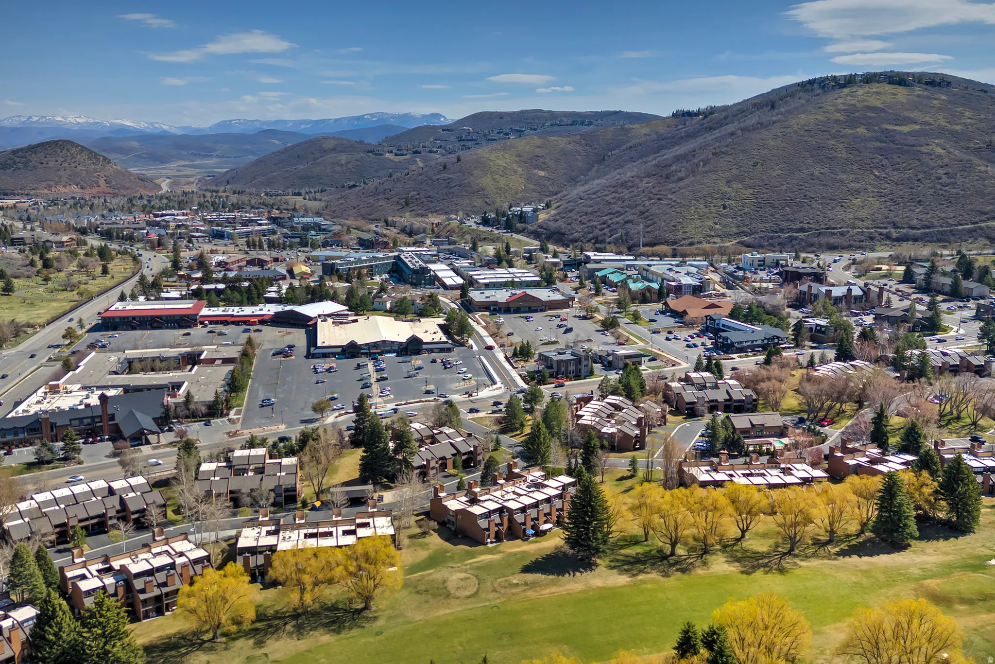 Expansive aerial capturing a vibrant community nestled among foothills with mountain backdrops