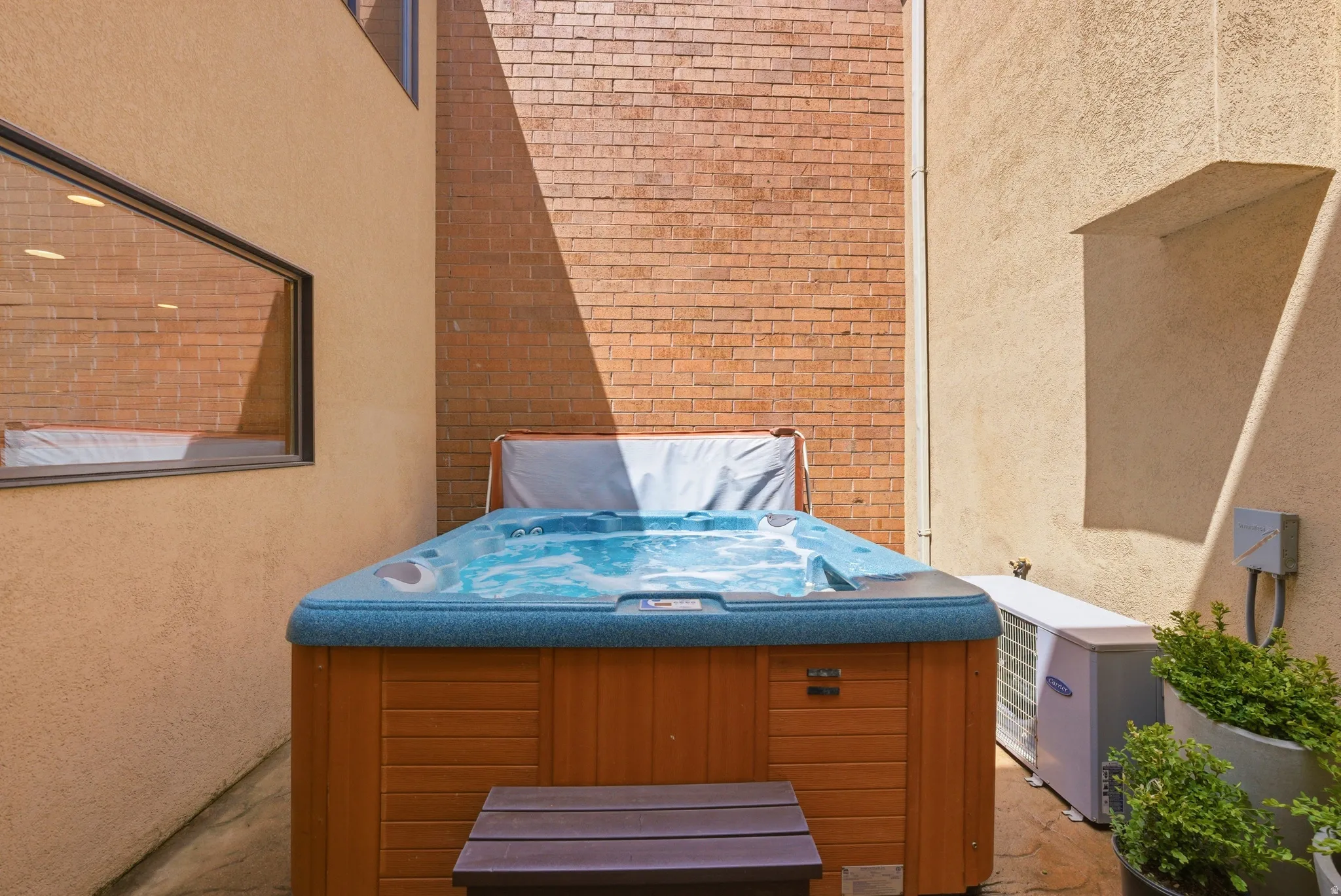 Outdoor spa featuring a wood-finish cabinet and a blue-toned interior