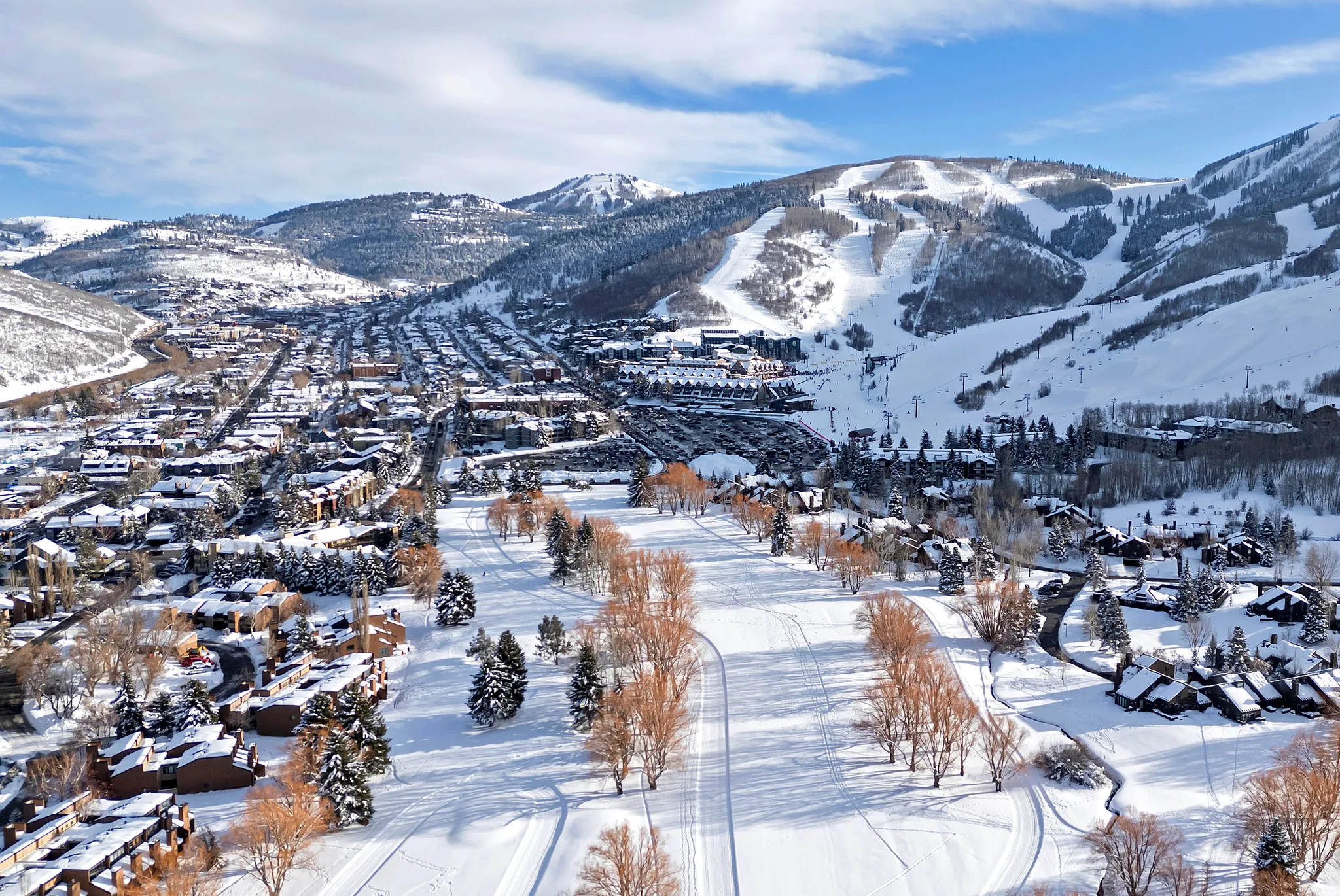 Expansive winter landscape featuring snow-covered mountain ranges and a valley with a town