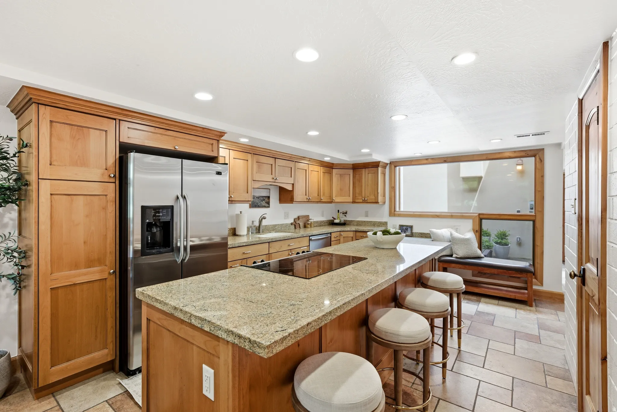 Kitchen featuring a large island with granite countertop, integrated cooktop, and seating for three