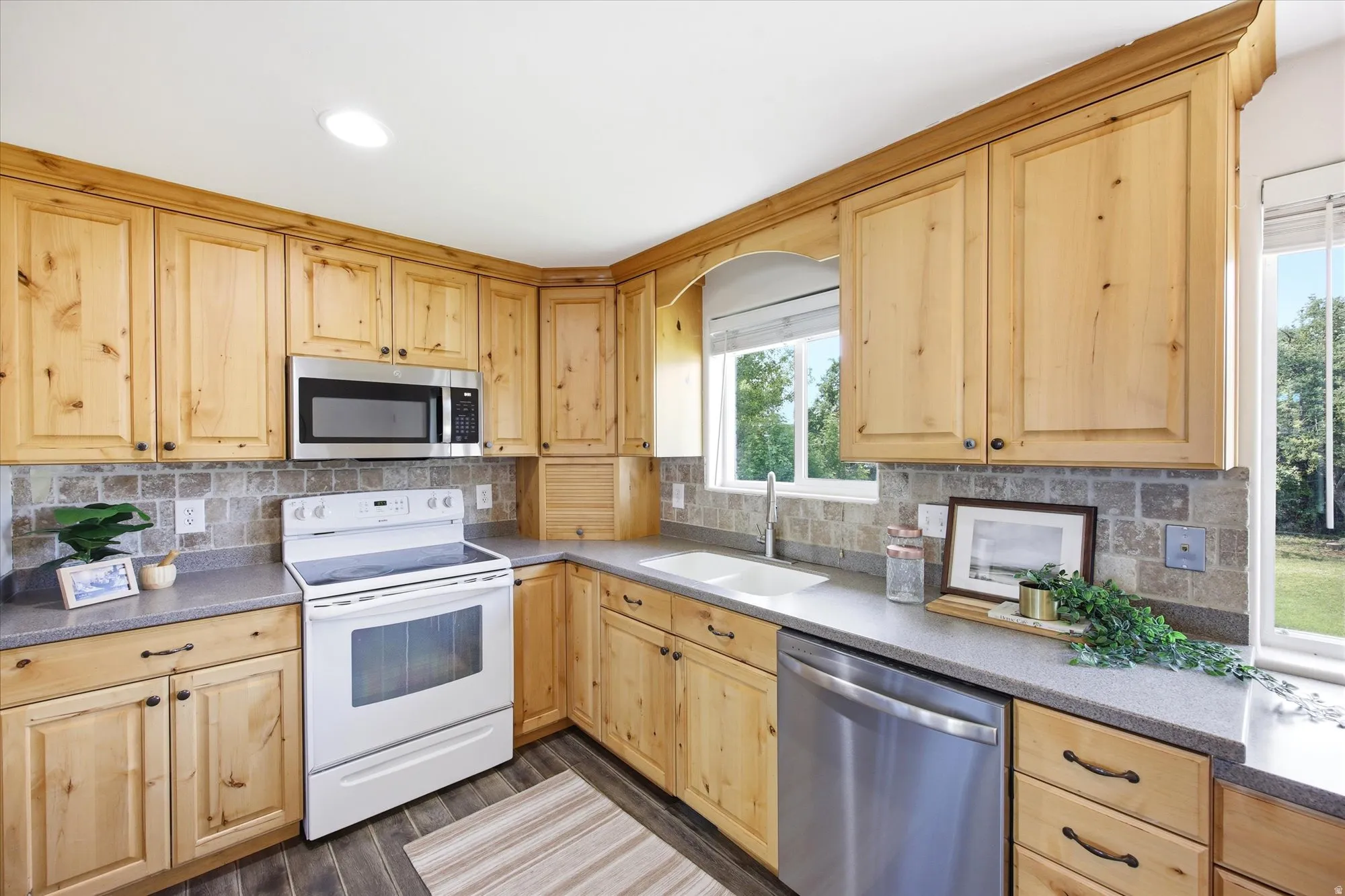 Updated Kitchen featuring knotty alder  cabinetry, stone tile backsplash, and dark wood-finish flooring
