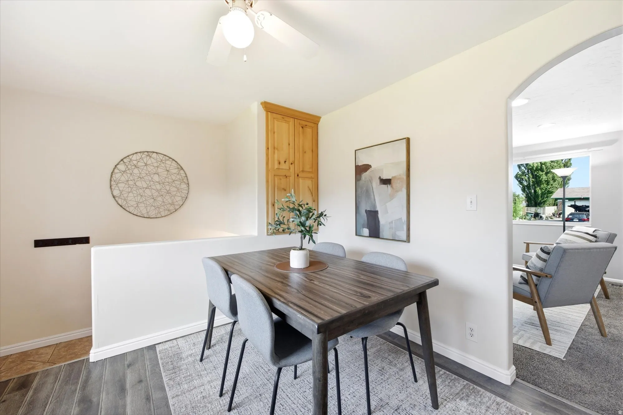 Dining area featuring wood-finish flooring, a ceiling fan with light fixture, and an arched doorway