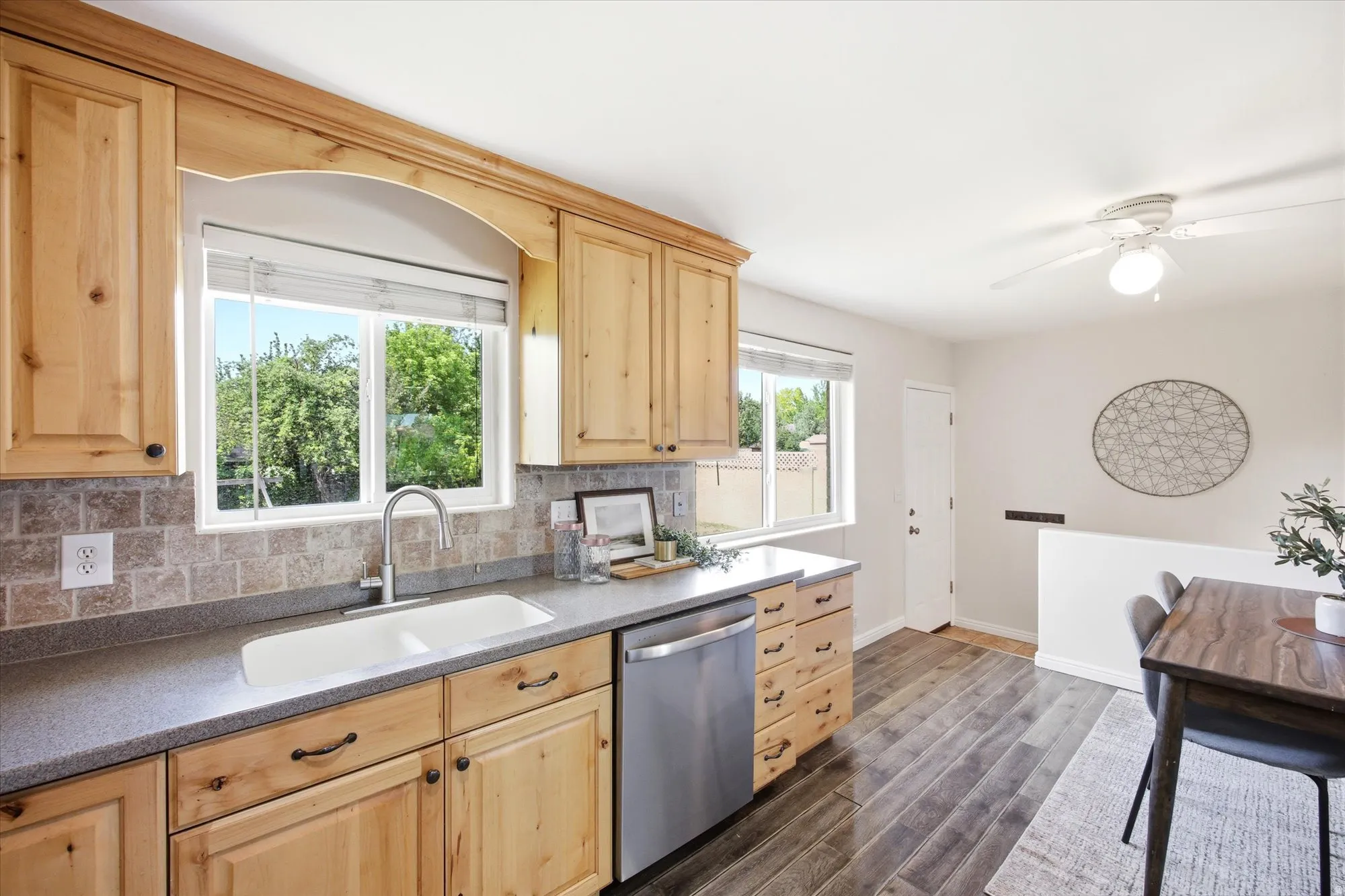 Kitchen featuring knoptty alder cabinetry, a stainless steel dishwasher, a double-basin sink, and mosaic tile backsplash