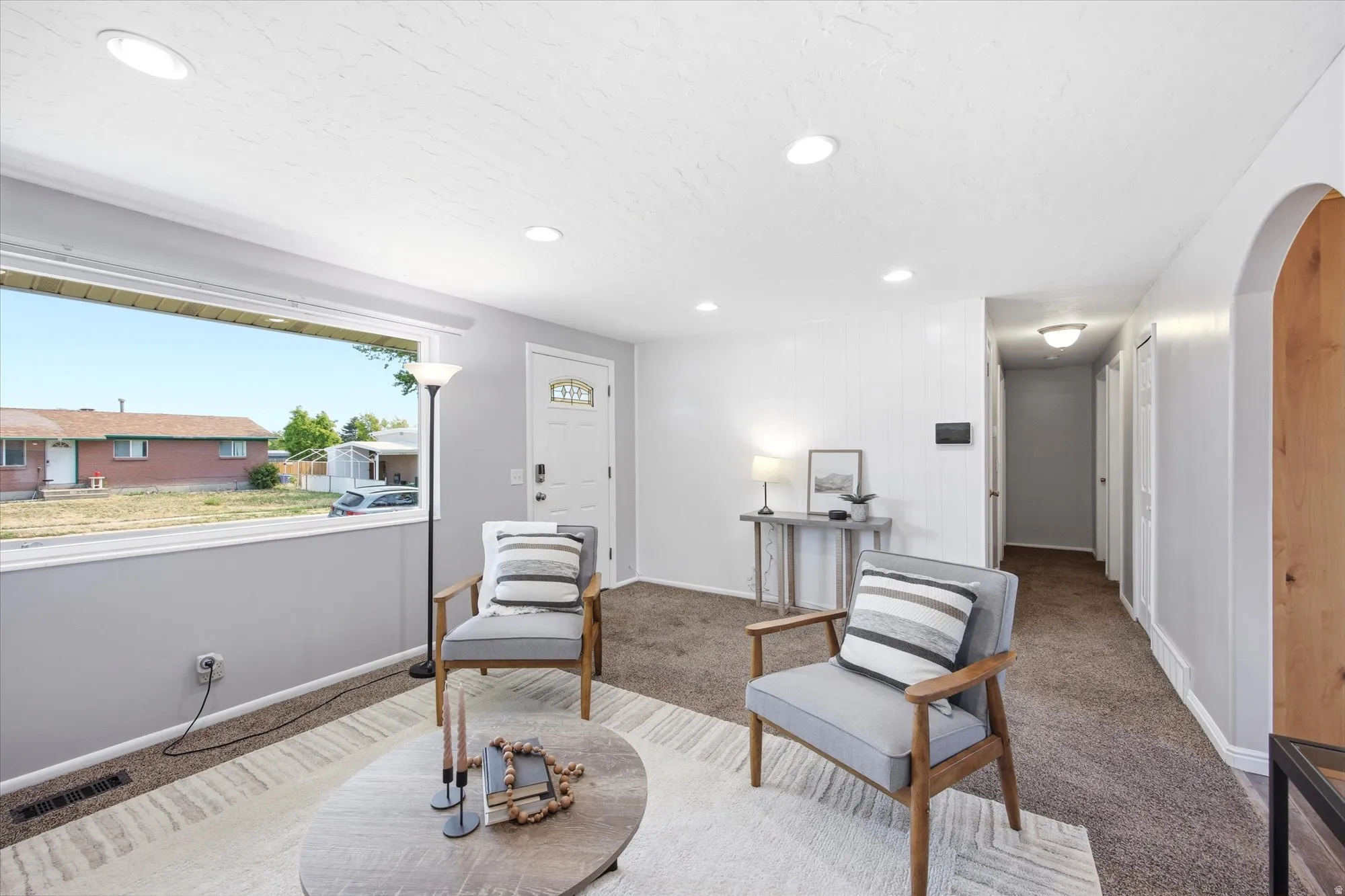 Bright living area featuring a large picture window, recessed lighting, and neutral tone carpeting