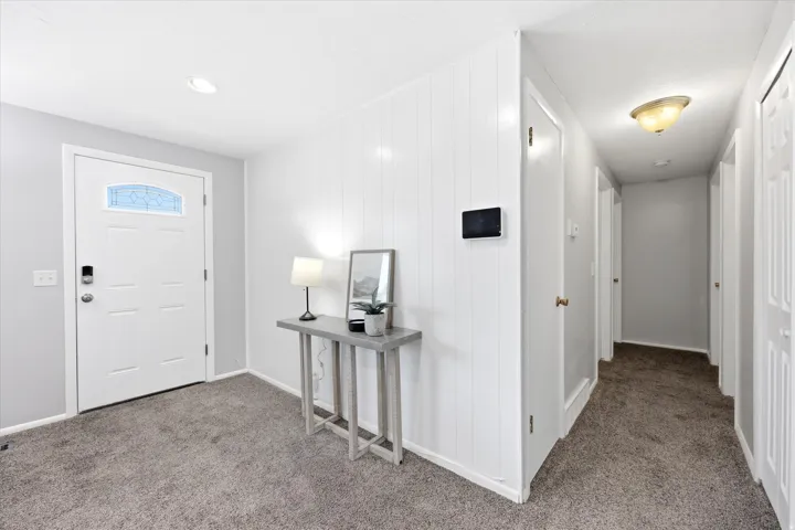 Entryway featuring a white paneled door with decorative glass, carpet flooring, and white vertical paneled wall accents