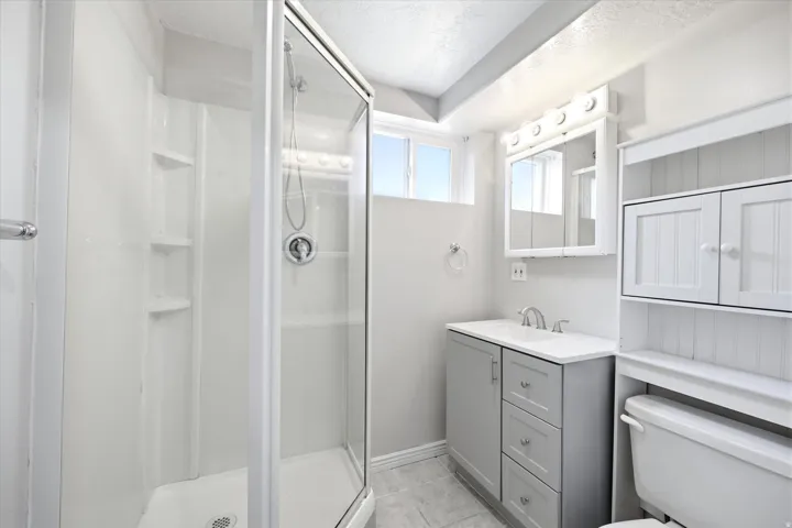 Shower stall featuring clear glass enclosure, built-in shelving, and chrome fixtures