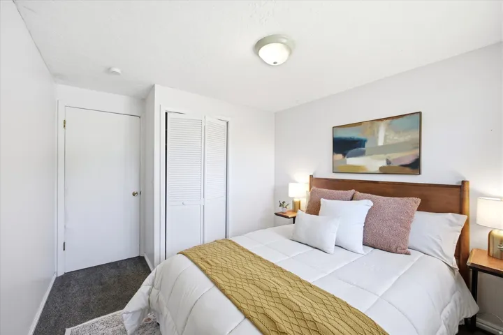 Bedroom featuring a wood headboard, white walls, and dark gray carpeting