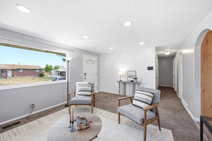 Bright living area featuring a large picture window, recessed lighting, and neutral tone carpeting