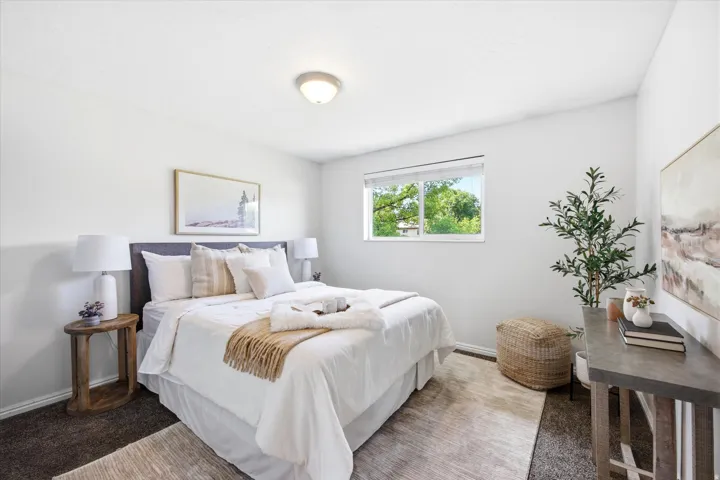 Bedroom featuring a single window with exterior greenery, neutral wall tones, and overhead flush mount lighting
