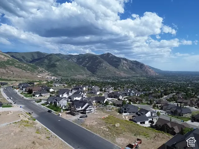 Expansive mountain backdrop with a residential community featuring a paved road and multiple single-family homes