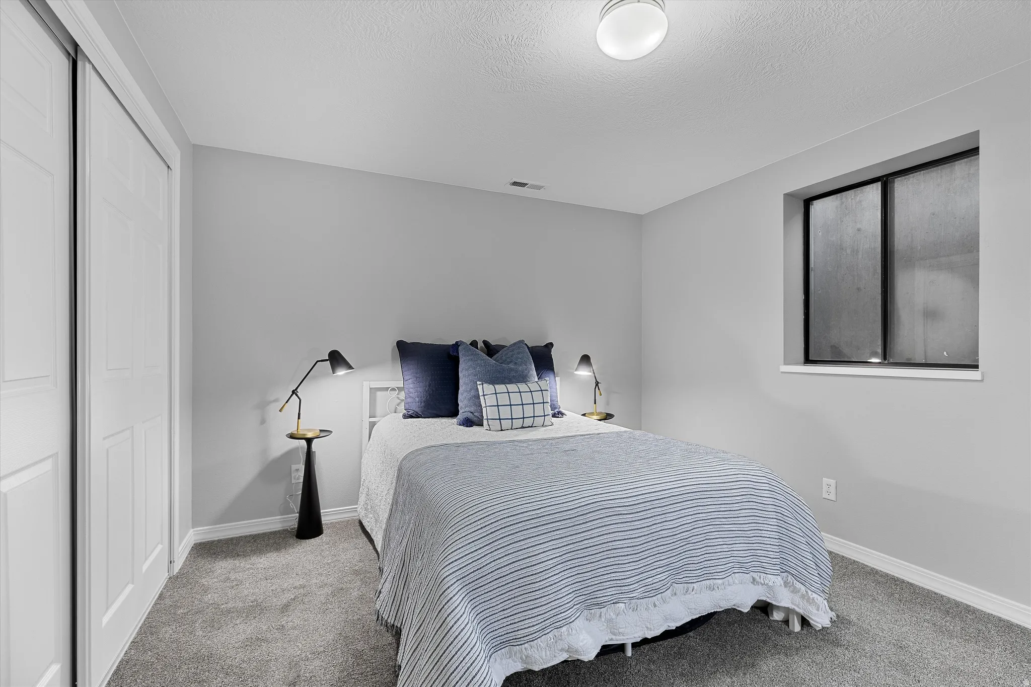 Additional Basement Bedroom. Carpeted bedroom with a window, white trim, and a flush-mount ceiling light