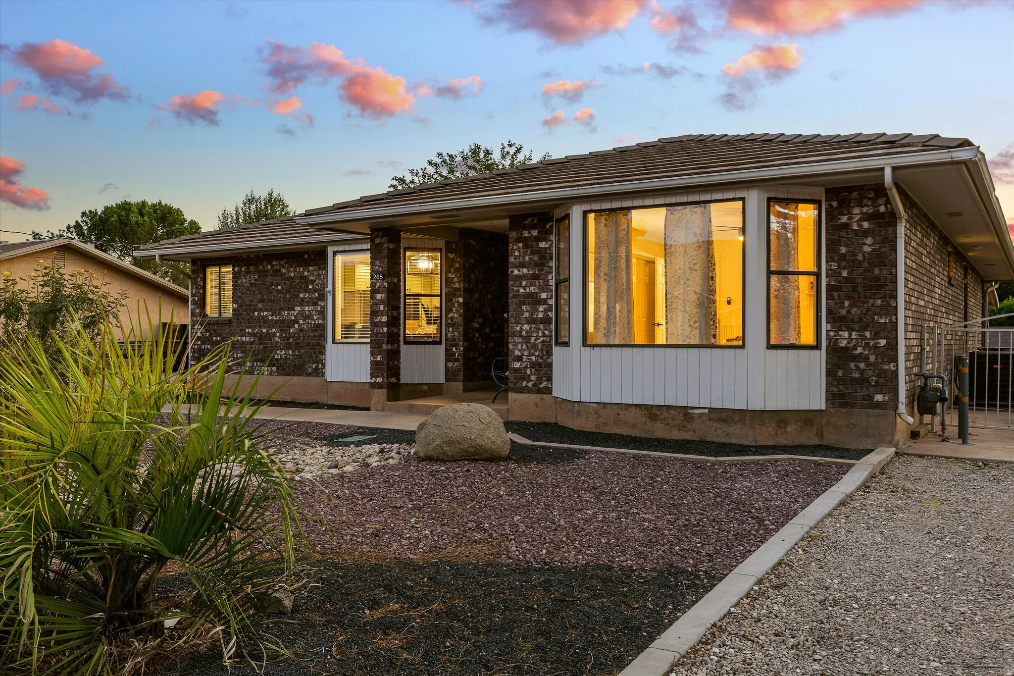 Front of Home at Twilight. Brick exterior featuring a prominent bay window, a covered entry, and a gravel driveway