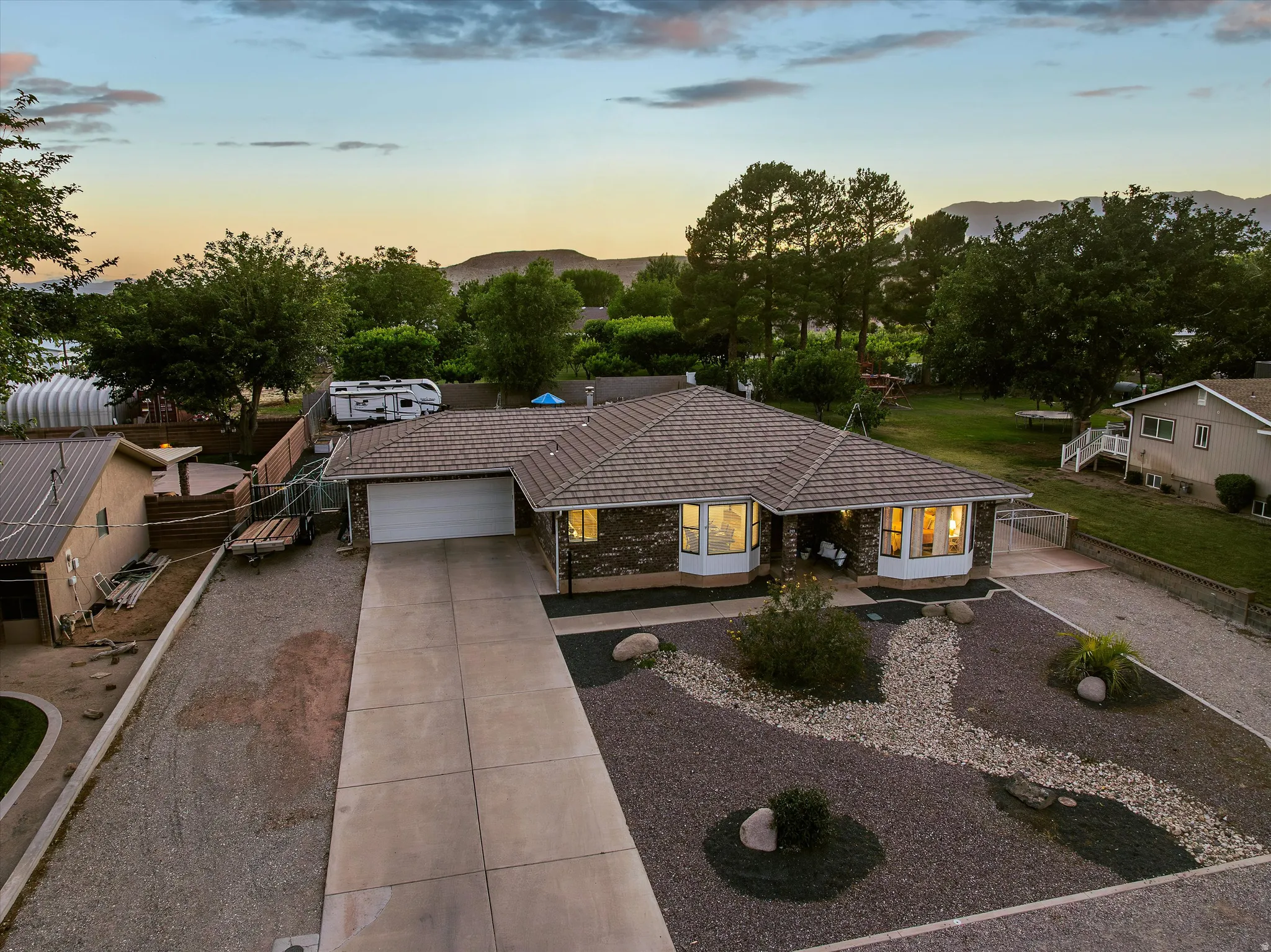 Front View at Sunset. Single-story residence featuring a durable tile roof, an attached garage, and bay windows