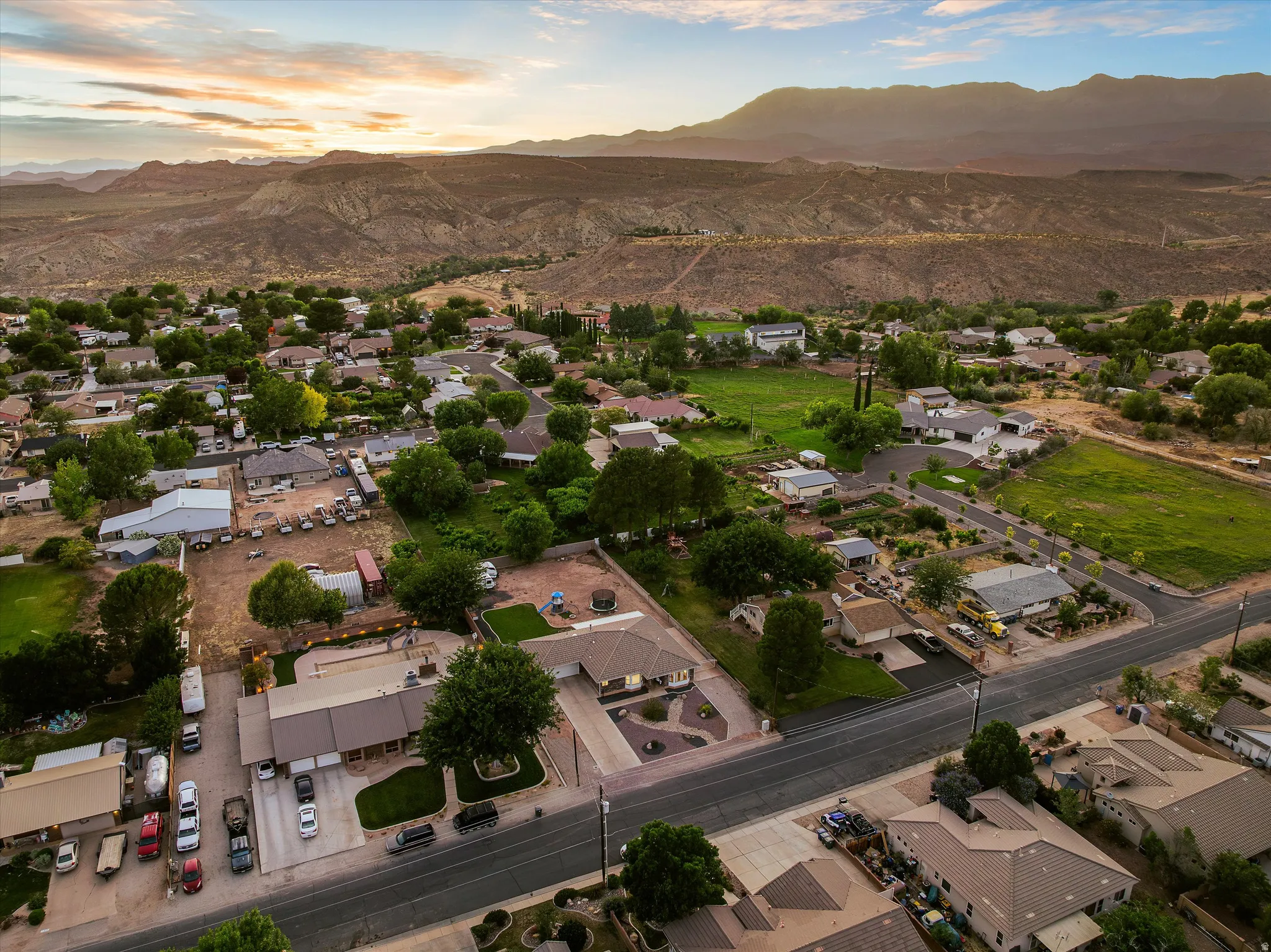Aerial at Sunset with Mountain Views. Aerial perspective showcasing a residential community with abundant mature trees and varied architectural styles