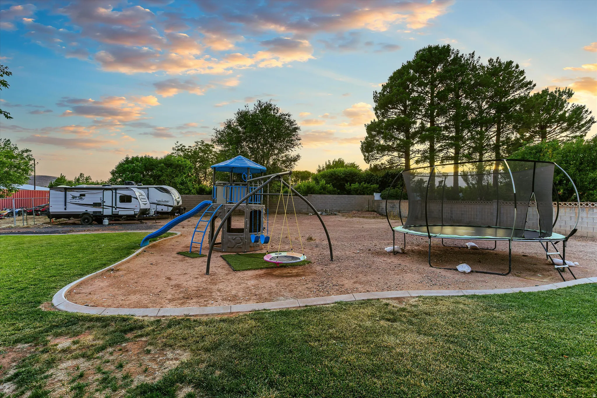 Backyard with Mature Trees & Room to Play. Expansive backyard featuring a dedicated play area with a swingset, slide, and trampoline