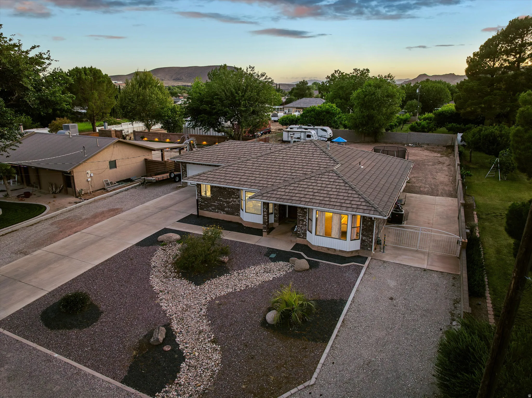 Aerial — Property & Front Yard. Single-story residence featuring a tile roof, stone accent facade, and a bay window