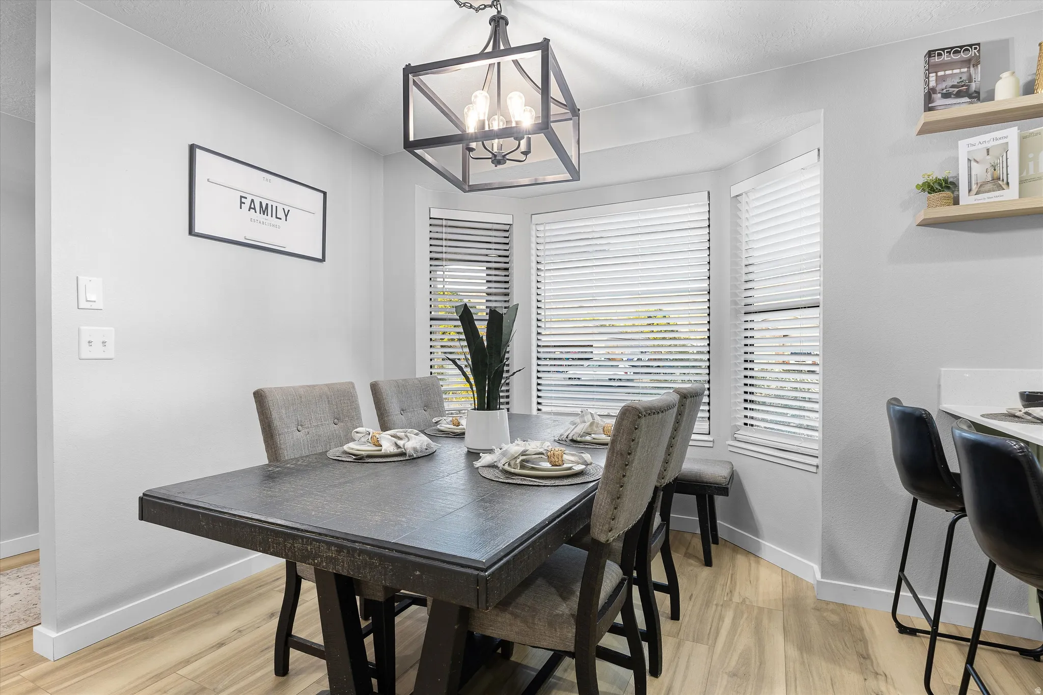 Dining Area with Statement Lighting. Dining area featuring a bay window, wood-finish flooring, and a contemporary chandelier