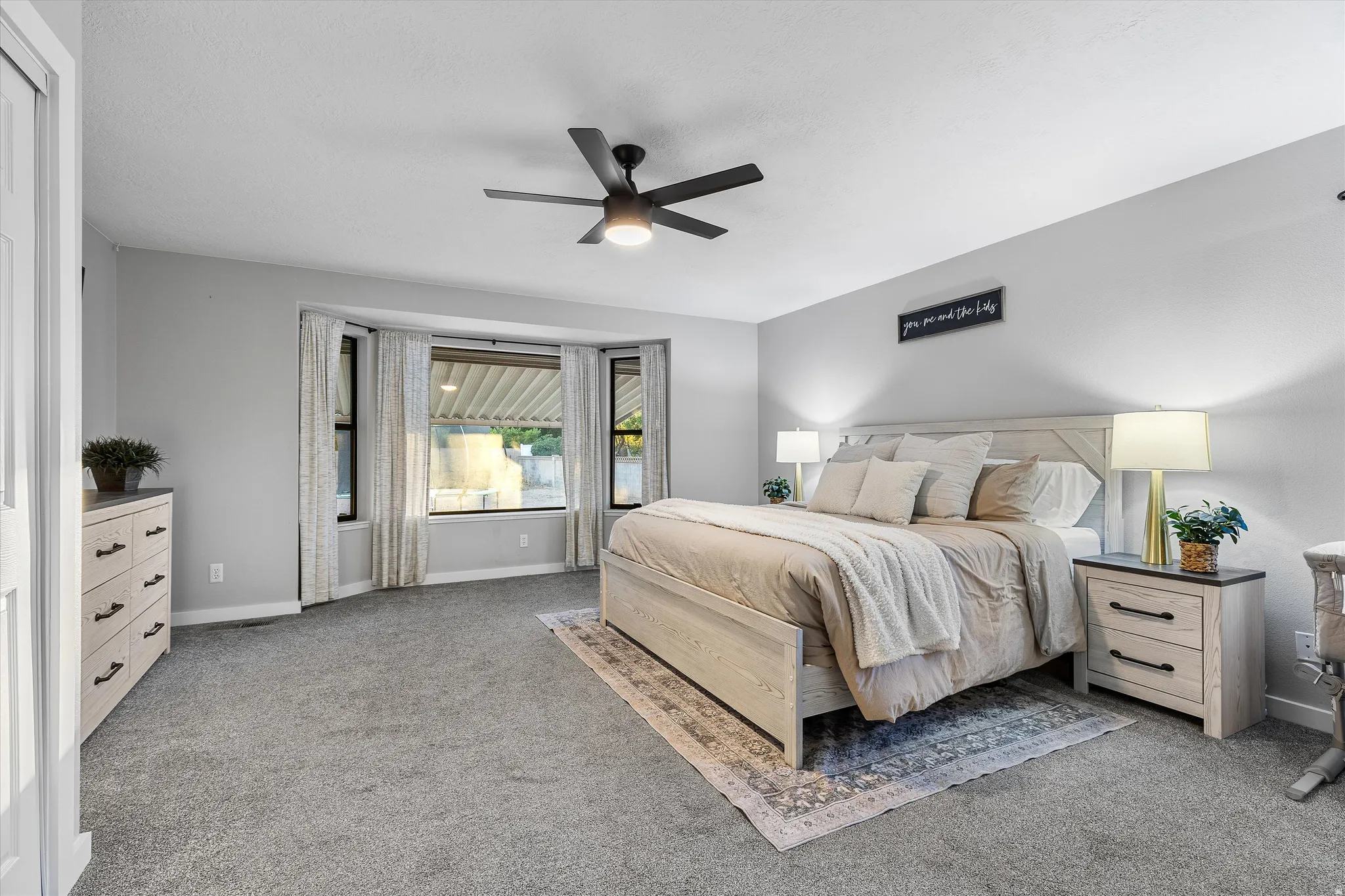 Primary Bedroom Retreat. Carpeted room featuring a bay window, ceiling fan, and light gray wall paint