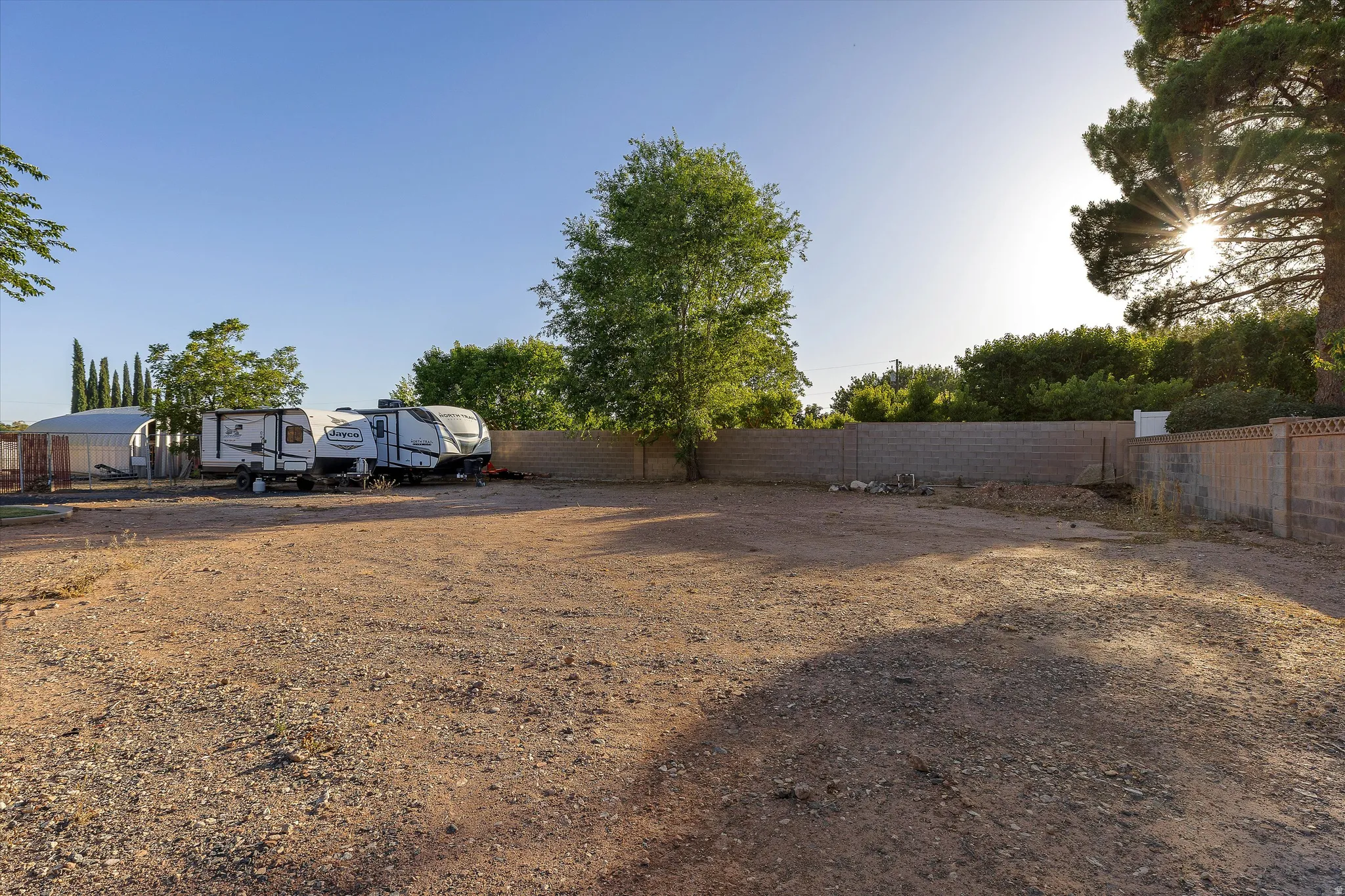Extended Yard with RV Parking. Expansive gravel lot featuring a partial block wall perimeter