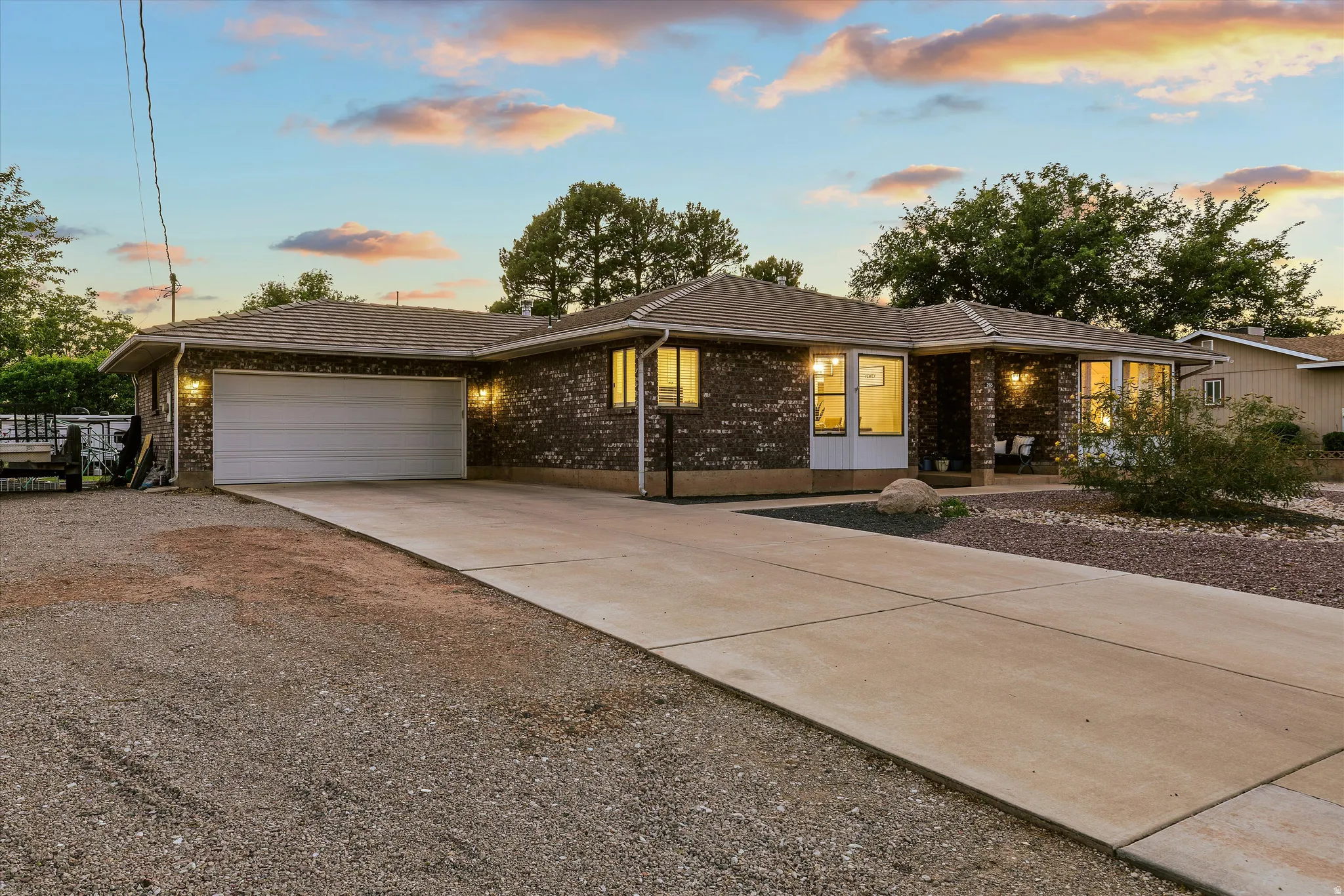 Driveway at Dusk. Brick exterior ranch-style home featuring an attached two-car garage