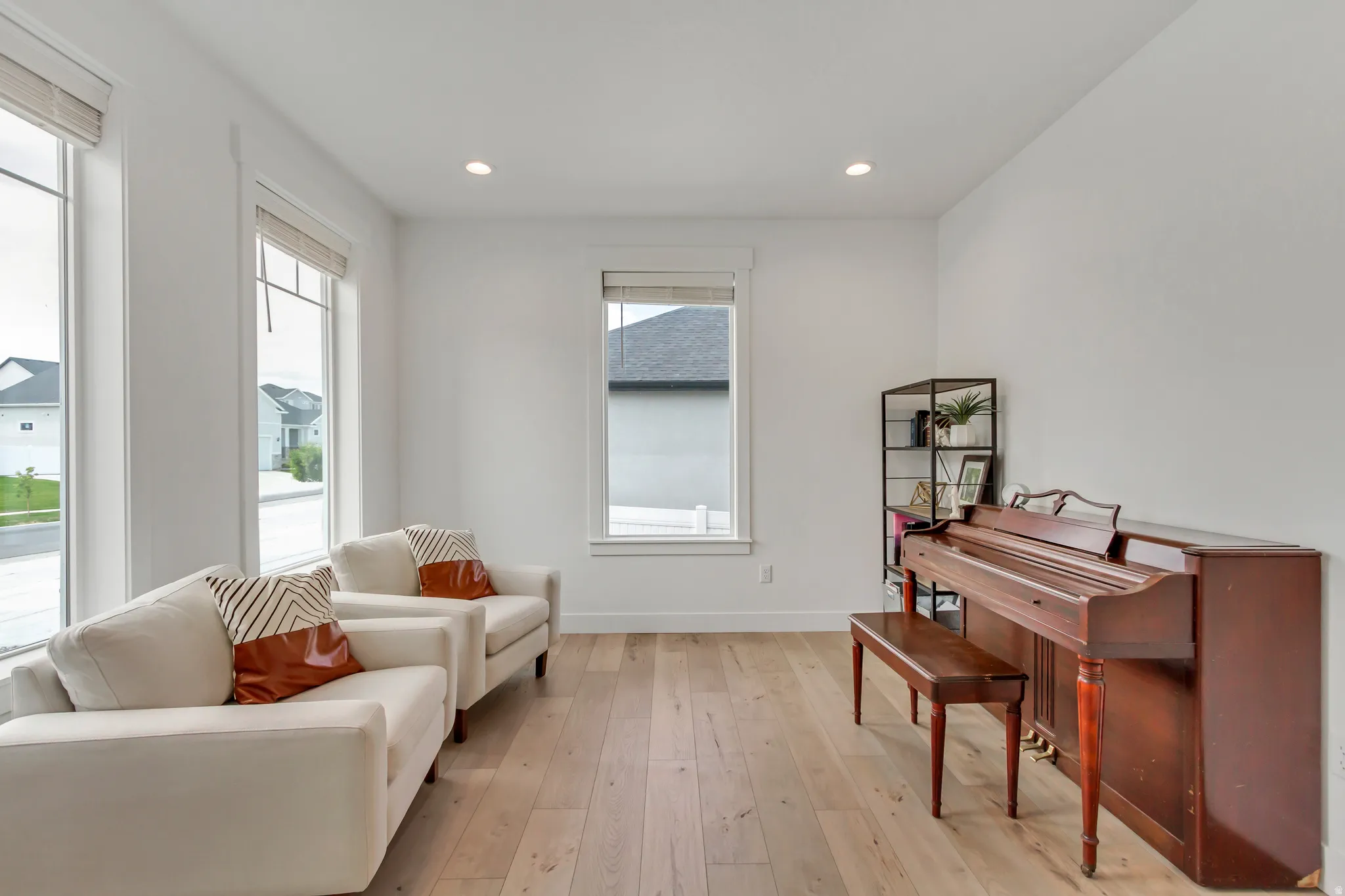 Office/living room/music room space featuring light wood-finish flooring, recessed lighting, and multiple windows with white trim