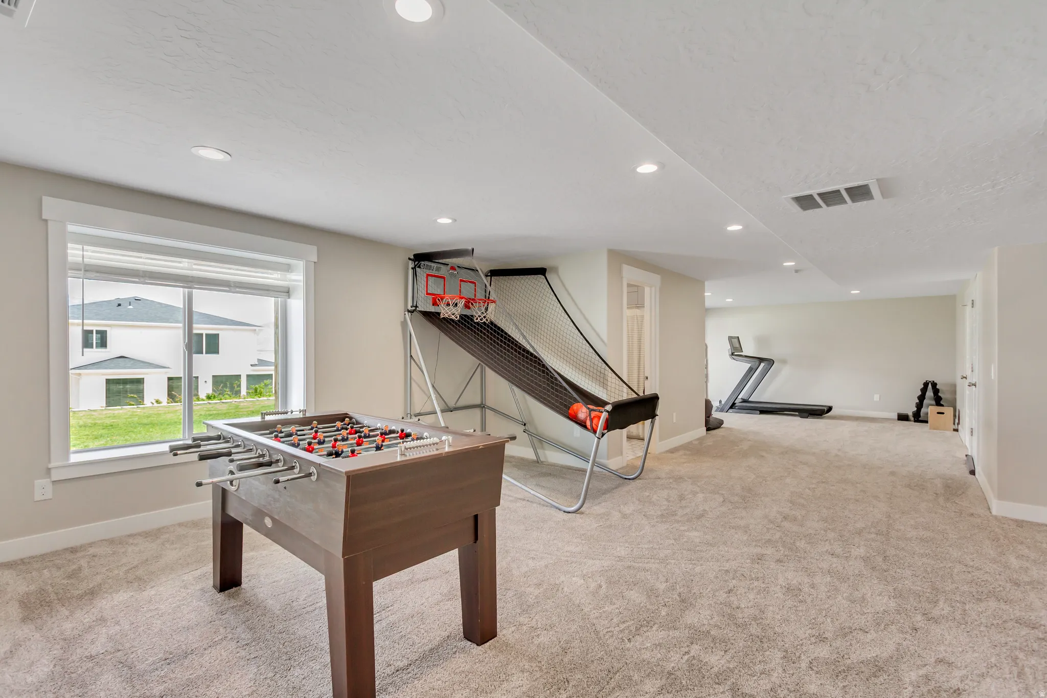 Spacious lower-level room featuring recessed lighting, a large window, light-colored carpeting, and light neutral wall paint