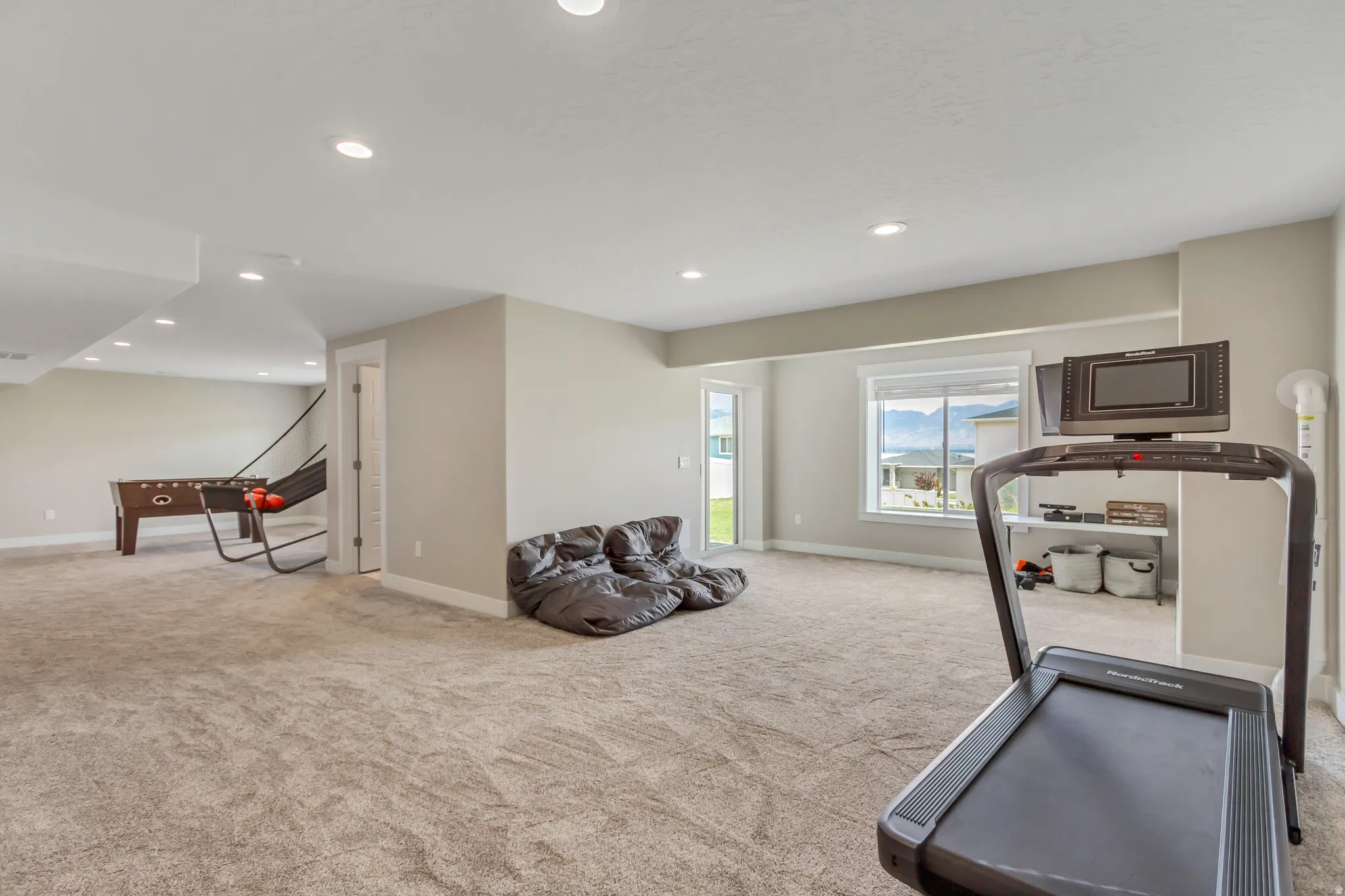 Spacious carpeted room with large window and sliding glass door to covered patio.
