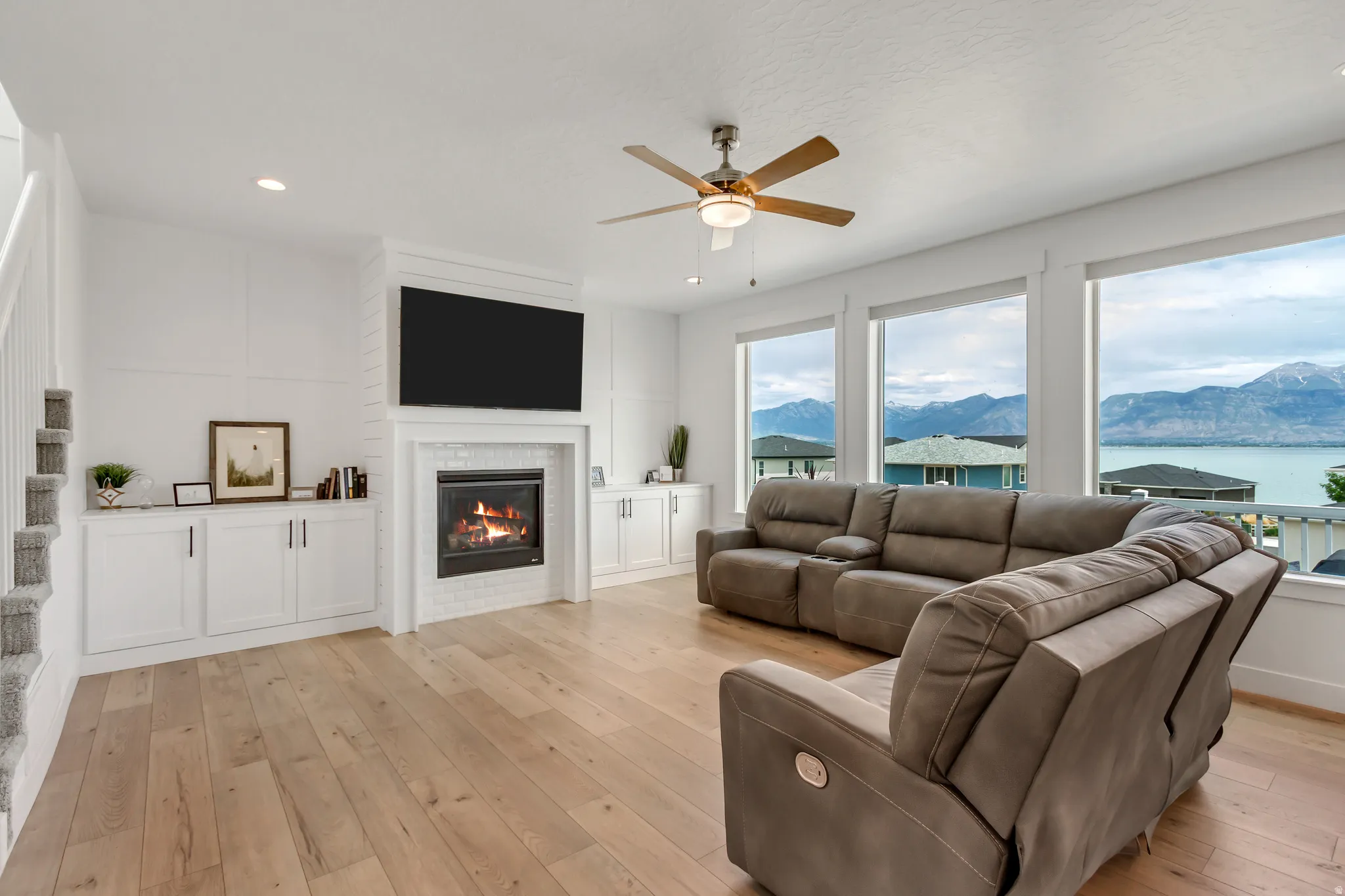 Spacious living area featuring a contemporary fireplace with white subway tile surround, built-in cabinetry, and a ceiling fan