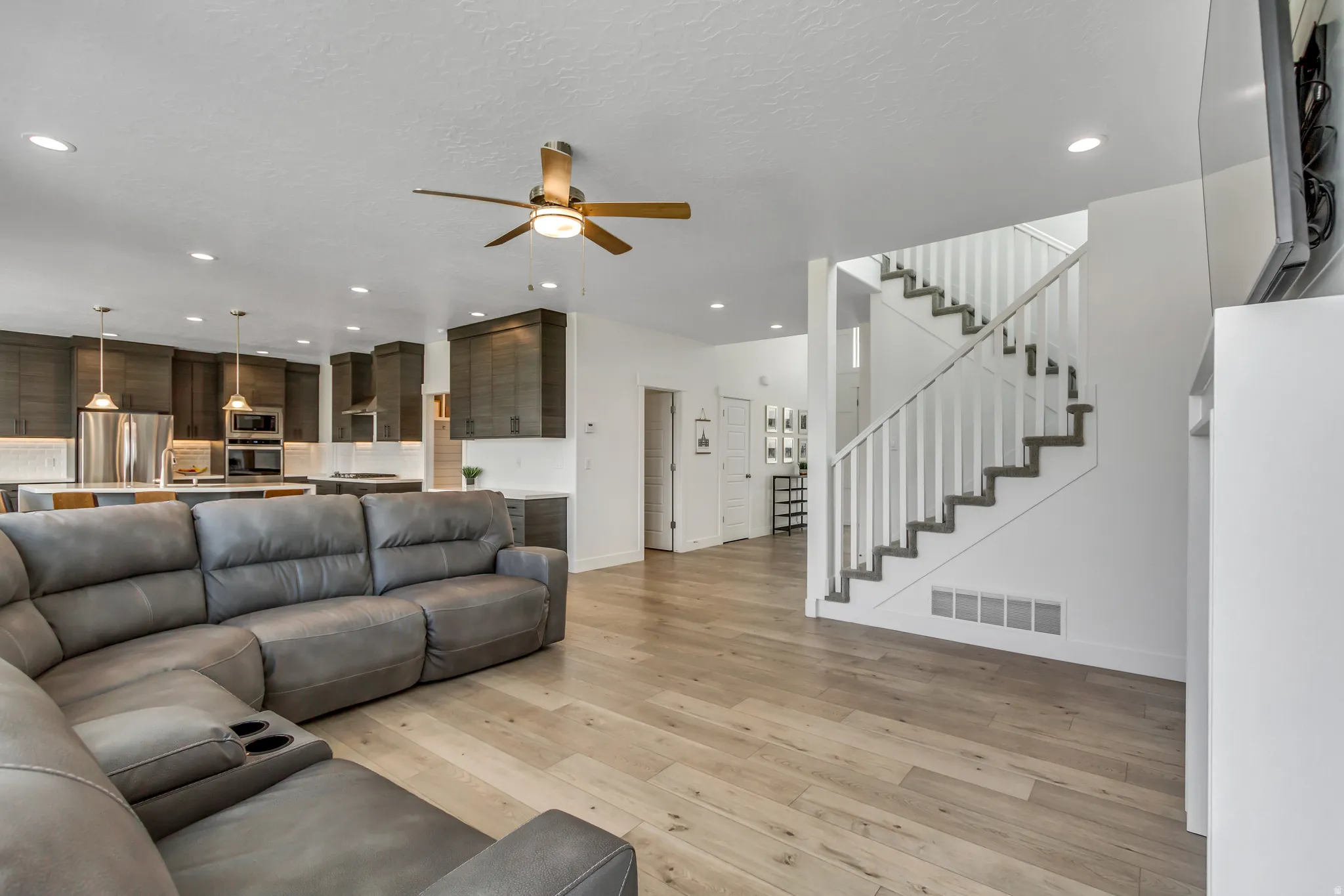 Open-concept living space featuring light wood-finish flooring, recessed lighting, and a ceiling fan