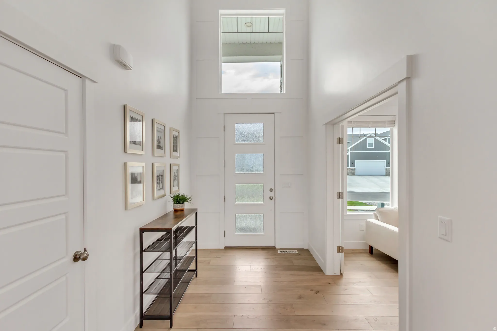 Entryway featuring light wood-finish flooring, a front door with multiple frosted glass panels, and a transom window above