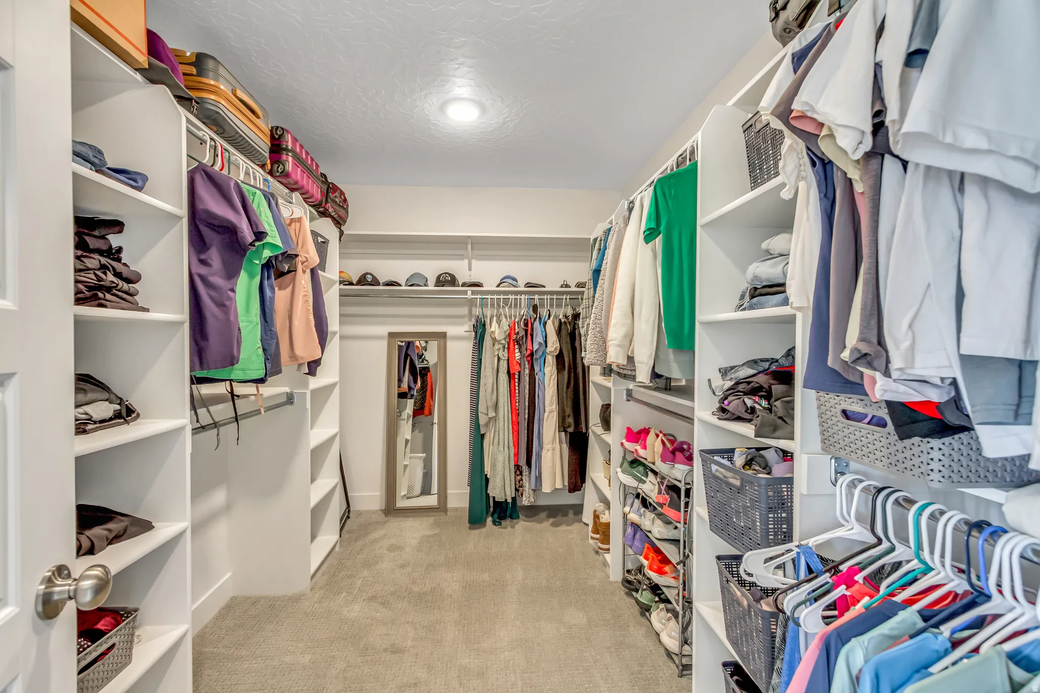 Primary walk-in closet featuring built-in shelving, multiple hanging rods, carpet flooring, recessed lighting