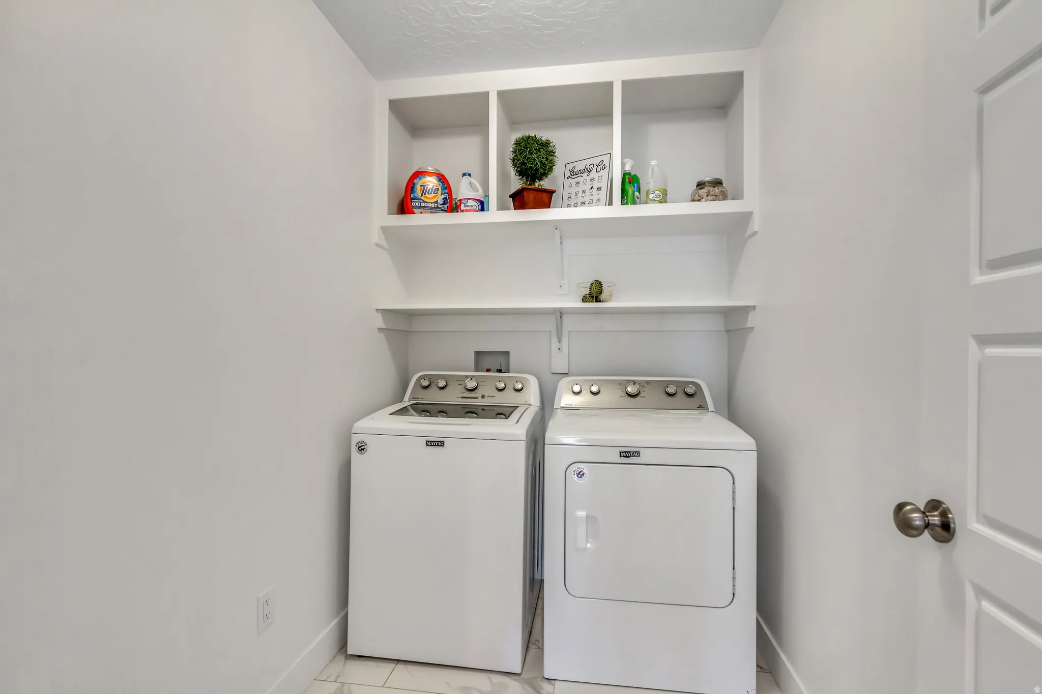 Dedicated laundry area featuring open shelving, and built-in cabinetry above