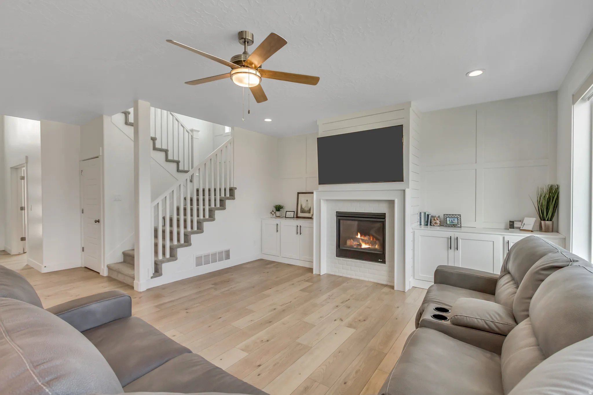Living area featuring wood-finish flooring, a contemporary fireplace with a white mantel, and built-in cabinetry