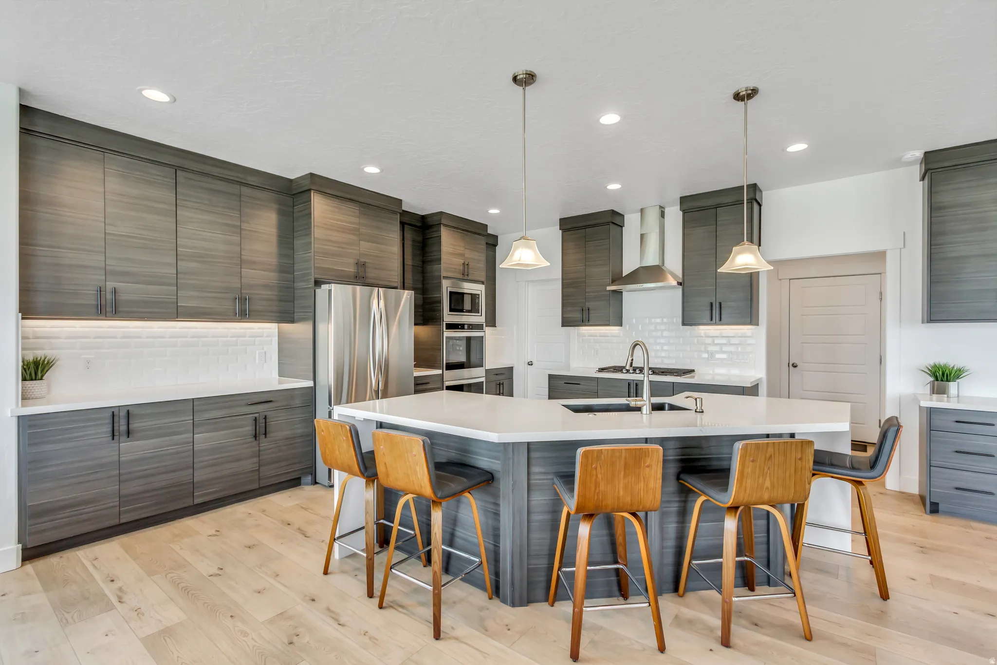Kitchen featuring a large multi-sided island with white quartz countertop, dark wood-finish cabinetry, stainless steel appliances, and recessed lighting