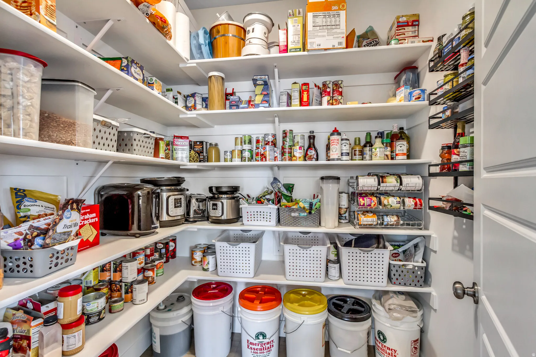 Walk-in pantry featuring extensive built-in shelving, white shiplap walls, and a white paneled door