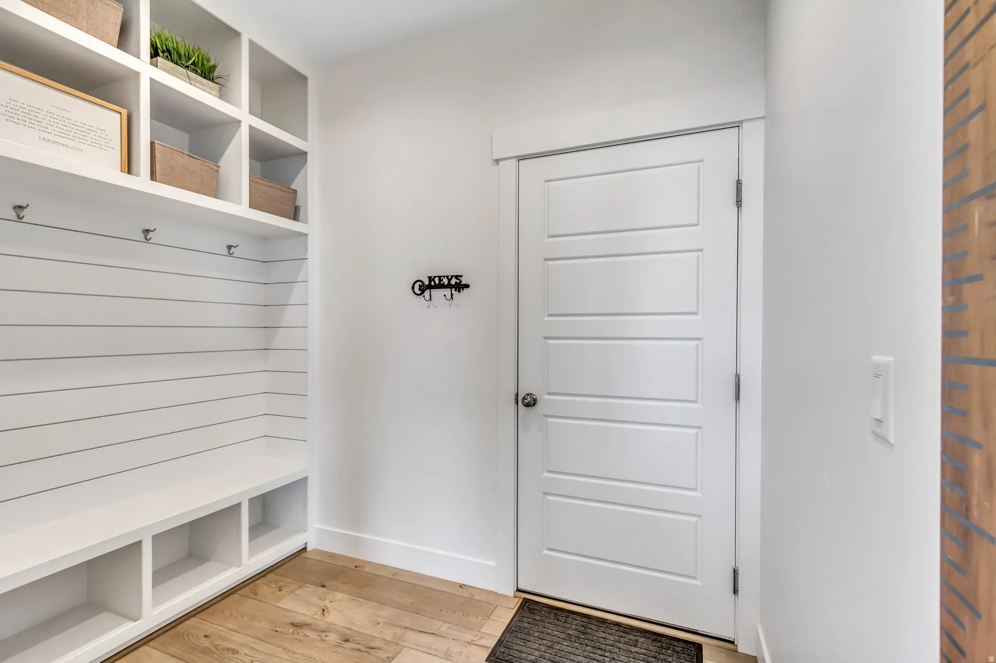 Built-in mudroom bench with cubby storage, shiplap backing, and overhead open shelving