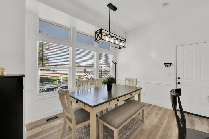 Dining area featuring a large window with transom panels, wood-finish flooring, and a modern rectangular chandelier
