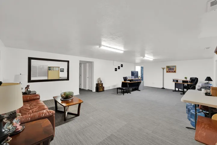 Spacious interior room featuring white walls, textured ceilings, and a combination of wood-finish and gray patterned flooring