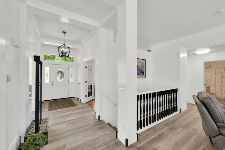 Entryway featuring a white paneled door with an oval glass insert, flanked by sidelights and a transom window