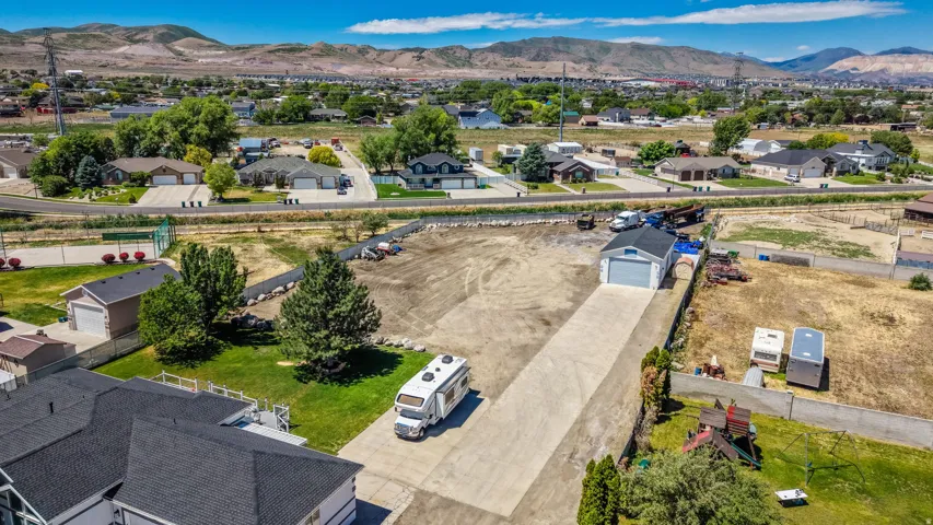 Expansive property featuring a large concrete driveway, a dedicated garage structure, and significant open land