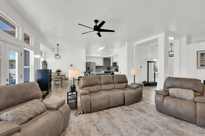 Open-concept living area with vaulted ceilings, wood-finish flooring, and a contemporary ceiling fan