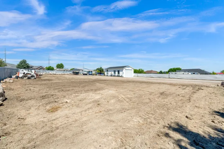 Expansive cleared lot featuring level ground and a distant white utility building