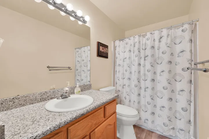 Bathroom featuring a vanity with a light-toned countertop, an integrated sink, a large mirror, and a full shower with a curtain