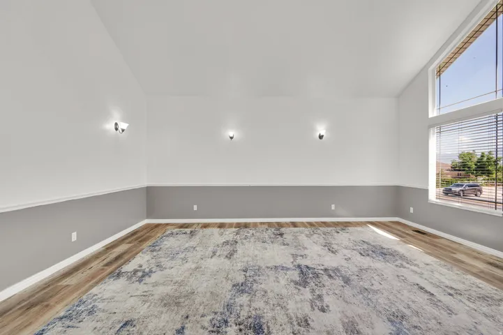 Spacious room featuring wood-finish flooring, two-tone wall paint, and multiple wall sconces