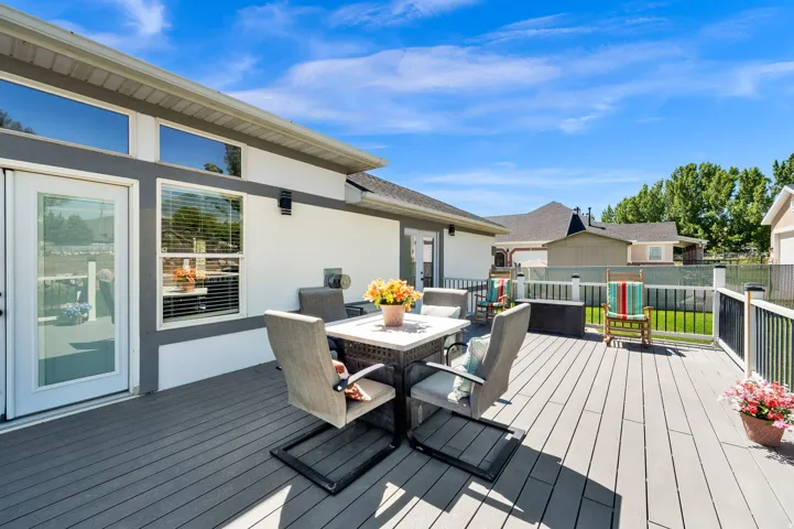 Expansive outdoor deck featuring composite decking, white and dark railing, and a full-light exterior door