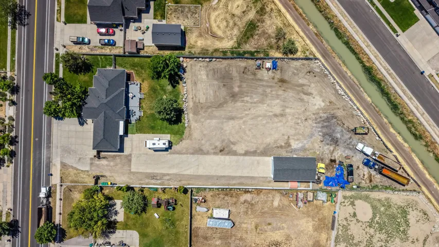 Expansive property featuring a multi-gabled main residence, a detached auxiliary building, and extensive paved and unpaved land areas