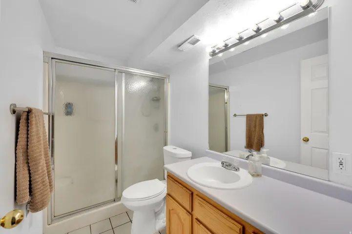 Bathroom featuring a white toilet, wood-finish vanity with a laminate countertop, and a shower with sliding glass doors