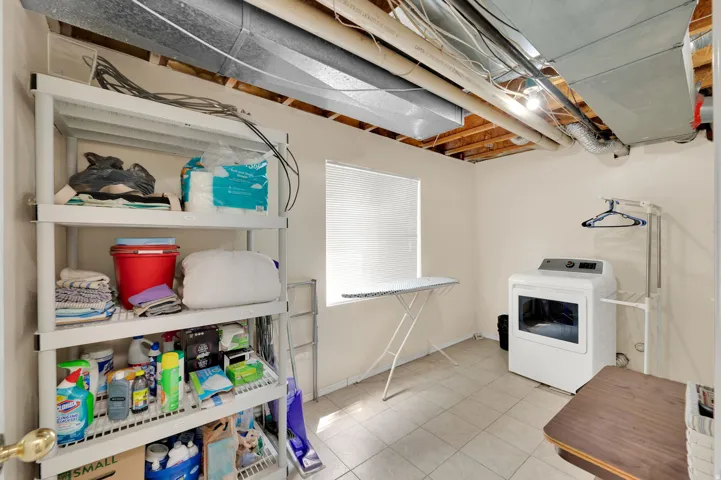 Utility room featuring light-toned tile flooring, a window with blinds, and white painted walls