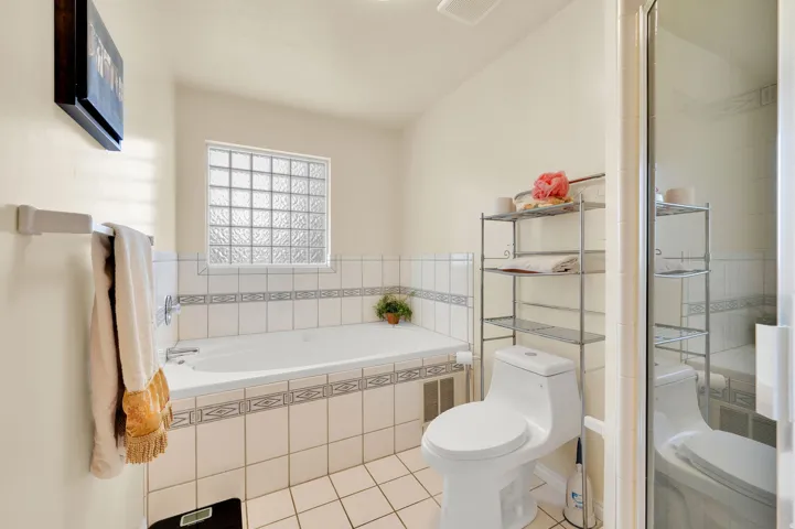 Bathroom featuring a built-in soaking tub with white tile surround, glass block window, and a separate shower enclosure