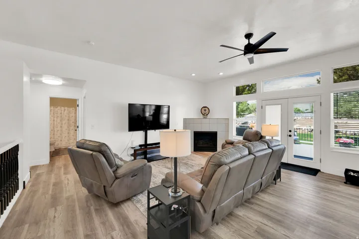 Open concept living area featuring wood-finish flooring, a ceiling fan, and a fireplace with tile surround